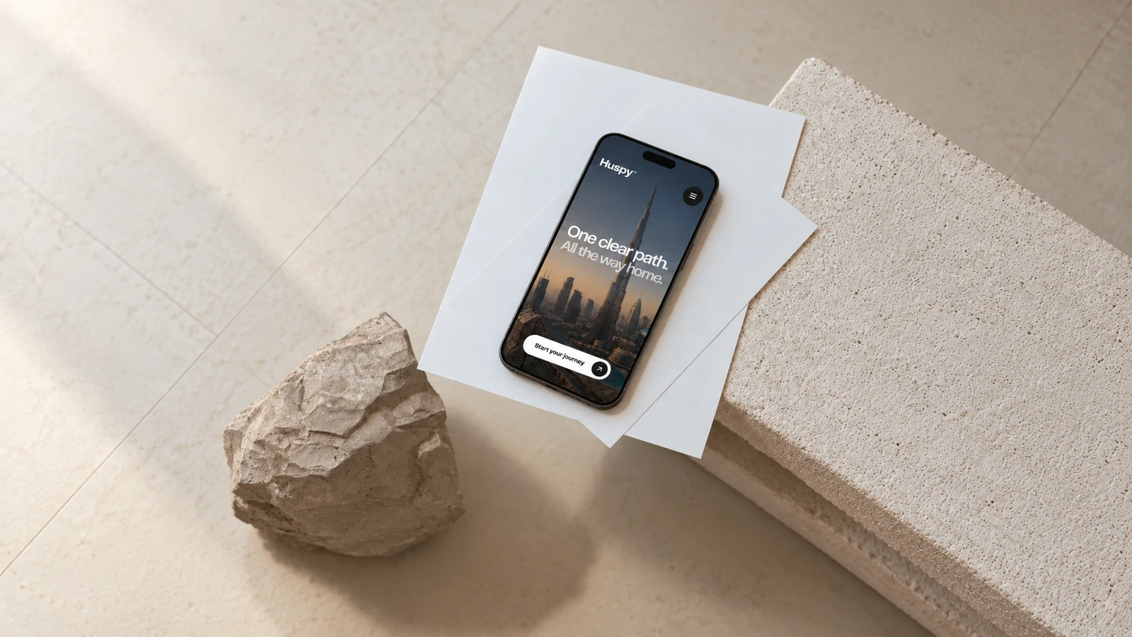 Huspy homepage mobile presentation on a phone among pale stones
